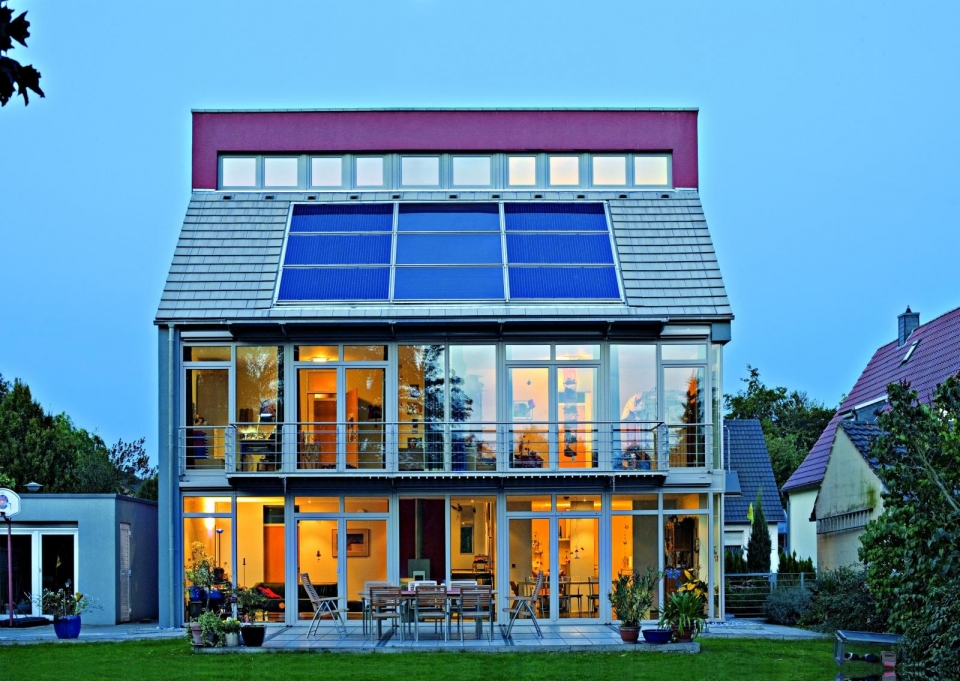Ein Haus mit Solarkollektoren und großer Glasfront