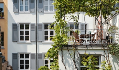dreistöckiges Haus mit grauen Fensterläden und Dachterasse