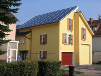 gelbes Haus mit Photovoltaikanlage 